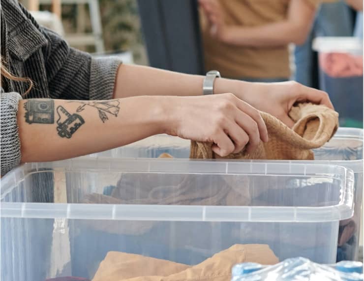 Someone placing clothing in a plastic tub