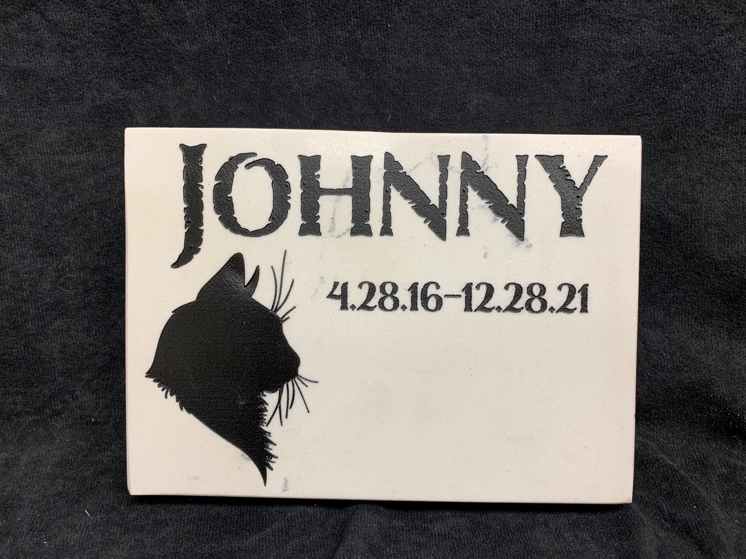 Pet headstone with a black carving of a cat and text that reads Johnny 4.28.16 - 12.28.21